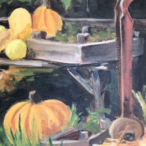 Table with gardening tools and several pumpkins and gourds on it. There is a fence and greenery in the background.
