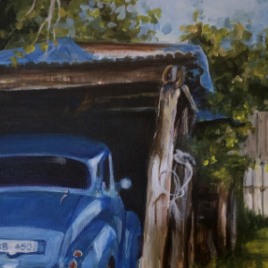 Back of blue car in a lean-to garage. There is a horseshoe hanging in the right top corner.
