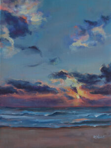 Sunrise over a sandy beach. Waves move towards the shore.